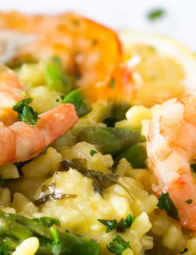 A dish piled high with yellow rice, asparagus and plump shrimp.