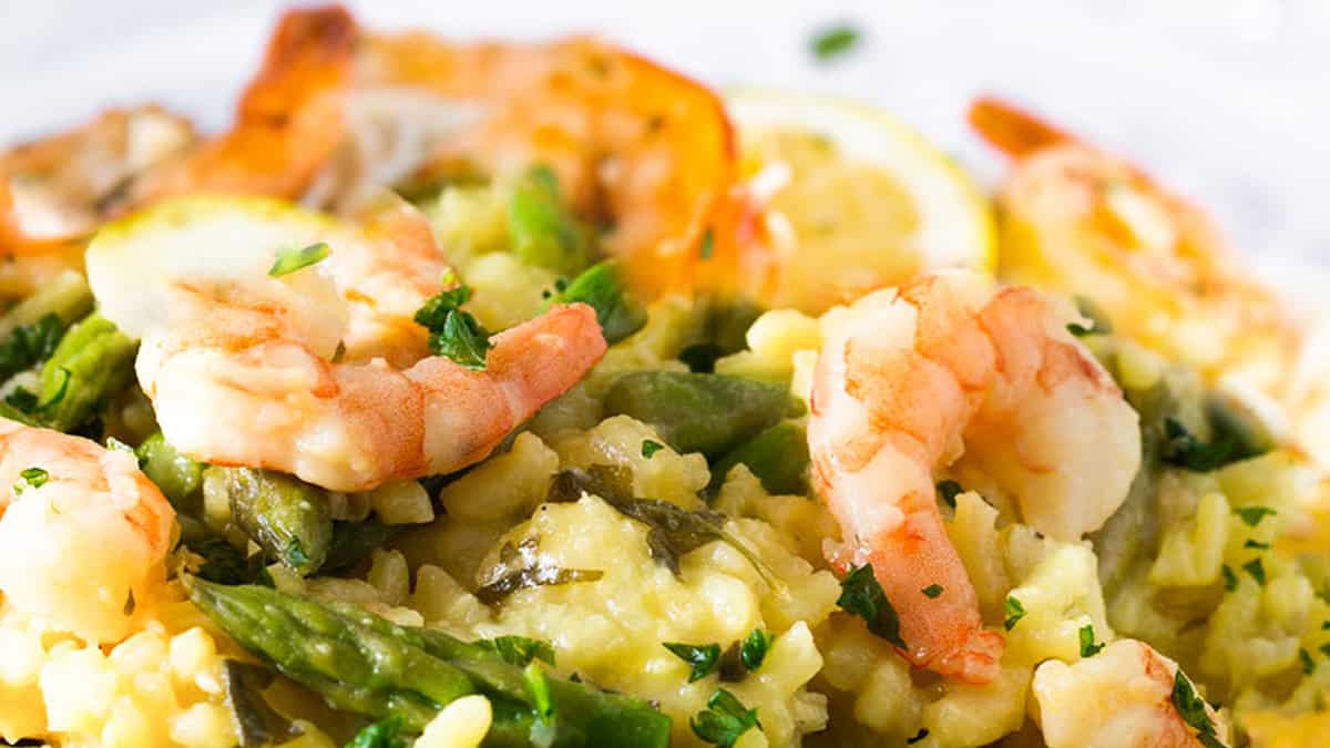 A dish piled high with yellow rice, asparagus and plump shrimp.