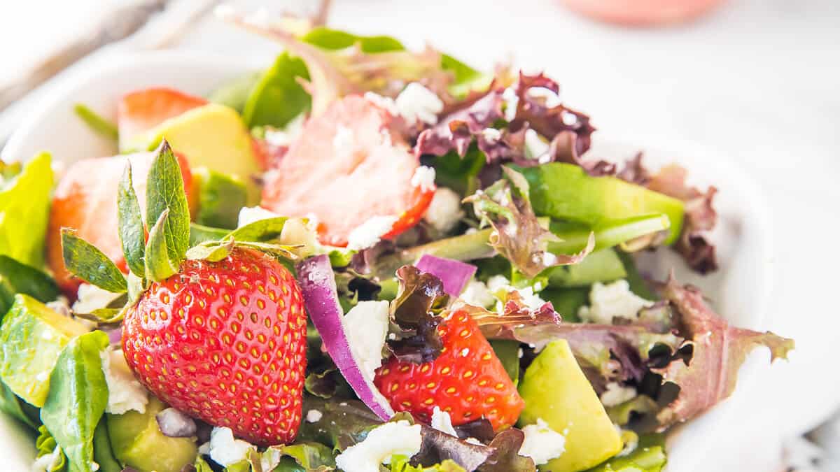 a close up image of a Strawberry Salad with greens, feta cheese and fresh strawberries.