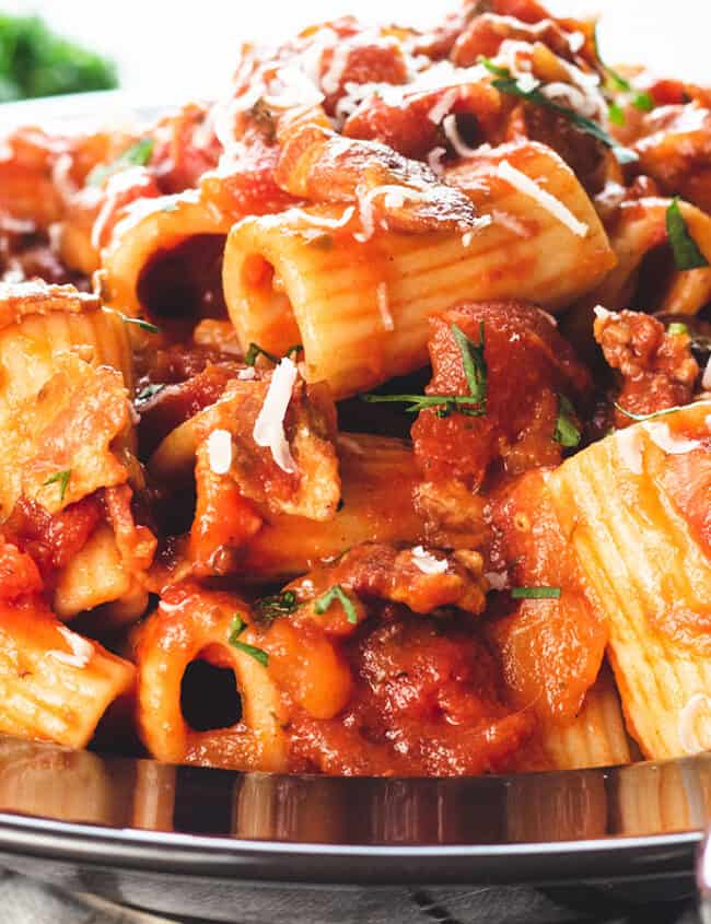 A heaping bowl of pasta with Amatriciana Sauce topped with grated cheese.