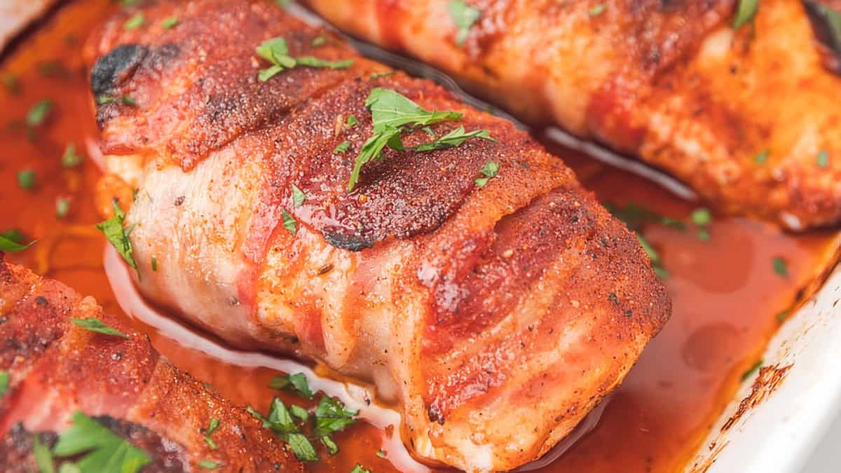 a close up image of a Bacon Wrapped Chicken Breast in a pan.