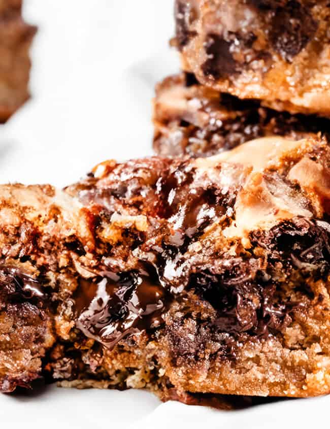 A close up image of a chocolate chip blondie with a gooey center exposed.