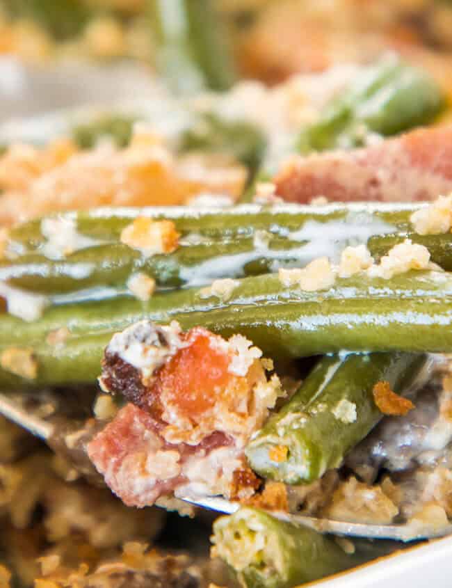 Green bean casserole with bacon being served with a spoon.