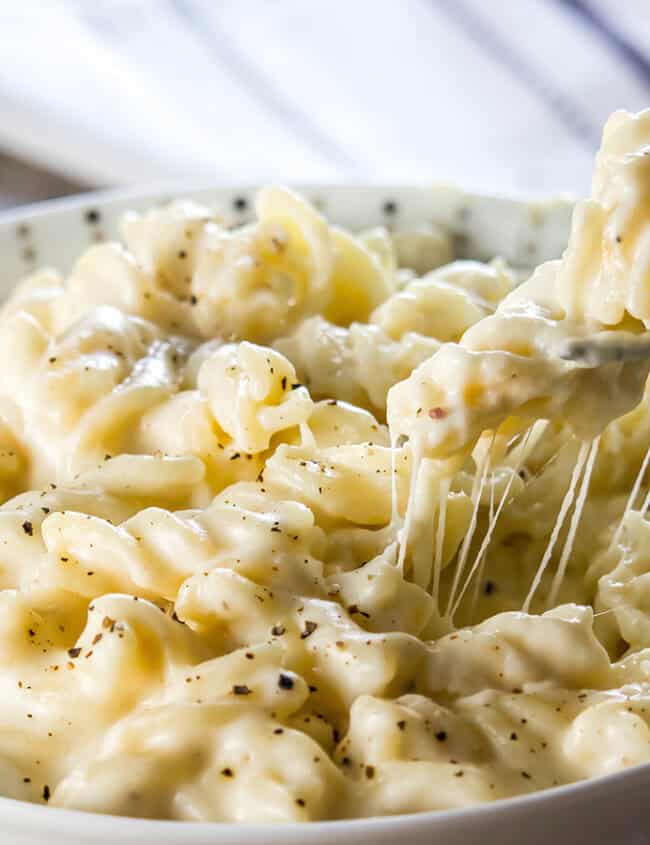 A fork digging into a big bowl of Homemade Creamy Mac and Cheese