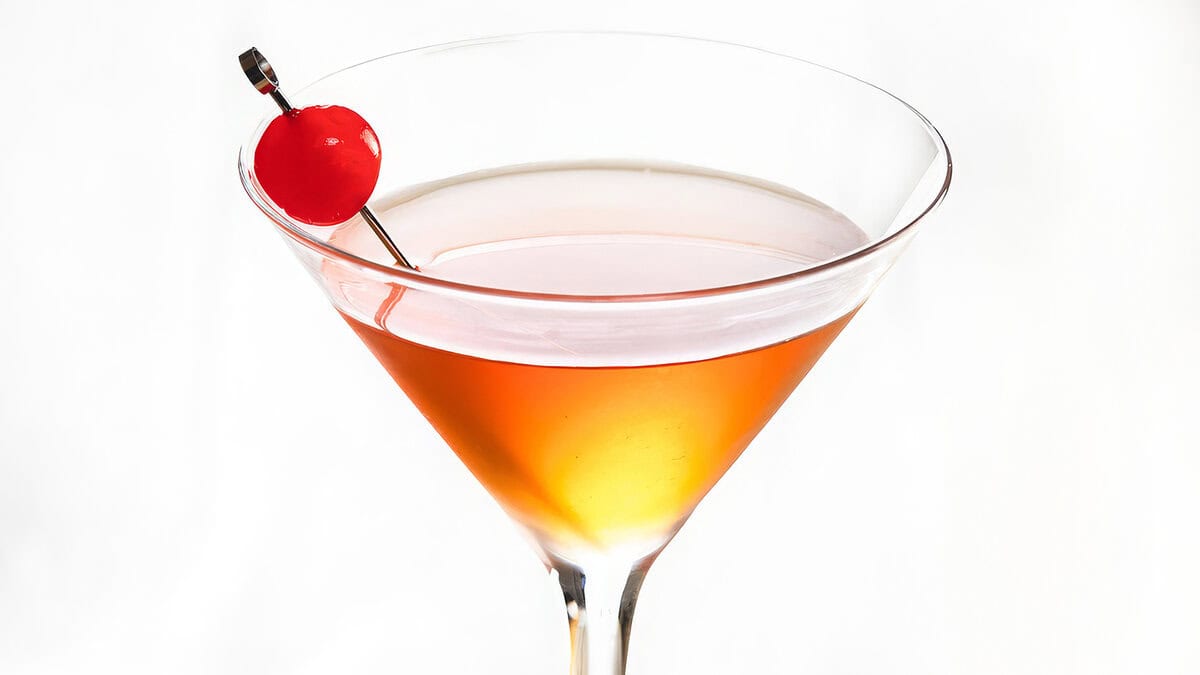 A cocktail glass with Manhattan drink and a cherry on a cocktail stick in the drink.