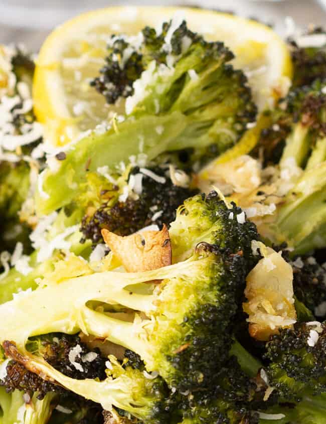 A close up of a plate of food with broccoli and lemons.