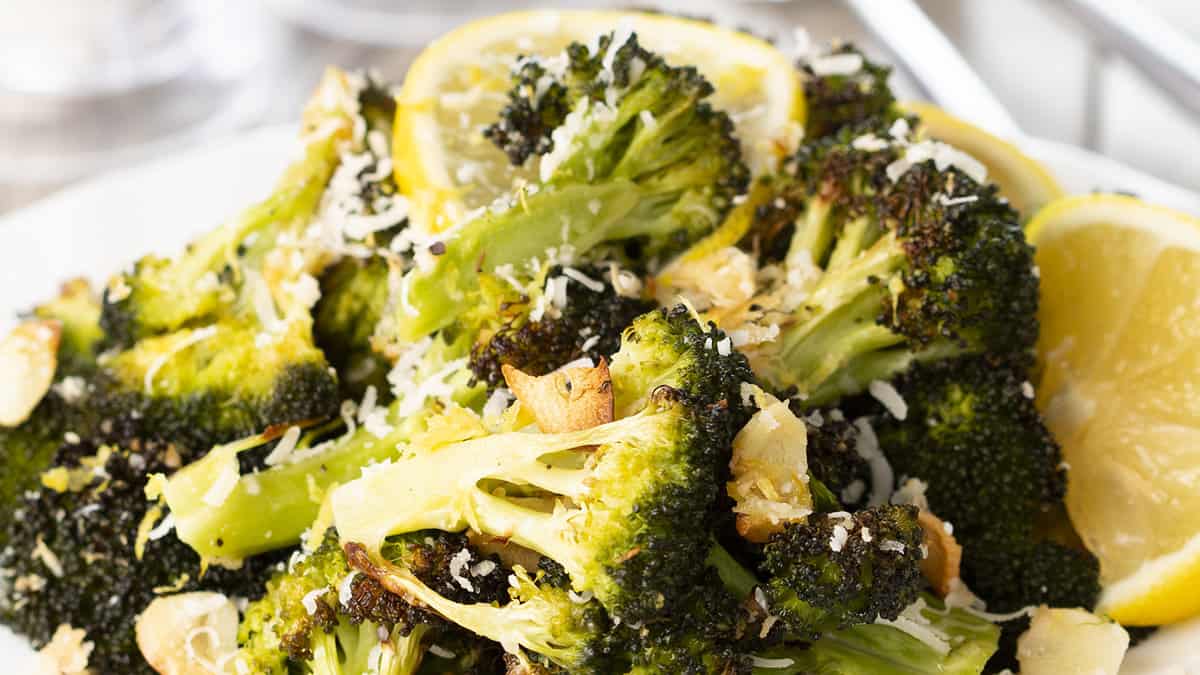 A close up of a plate of food with broccoli and lemons.