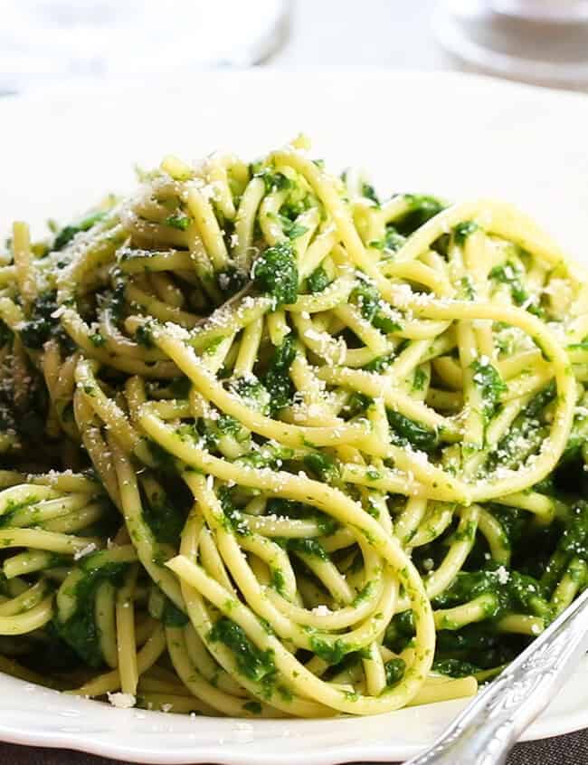 A bowl of Spaghetti with Spinach Sauce with a fork next to it on the plate