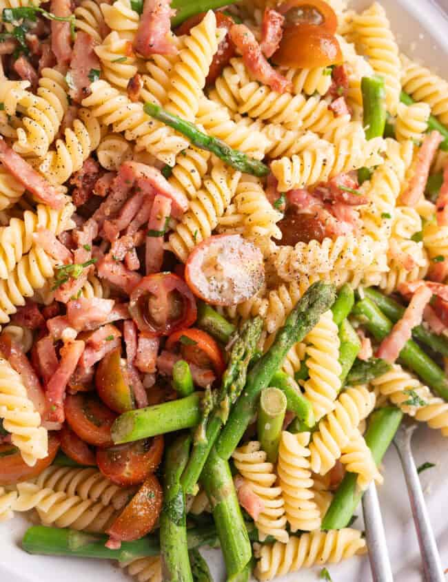 A colorful pasta salad made with asparagus, cherry tomatoes, and crumbled bacon.