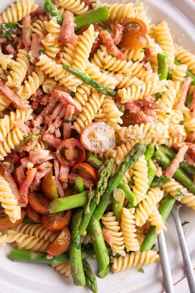 A colorful pasta salad made with asparagus, cherry tomatoes, and crumbled bacon.