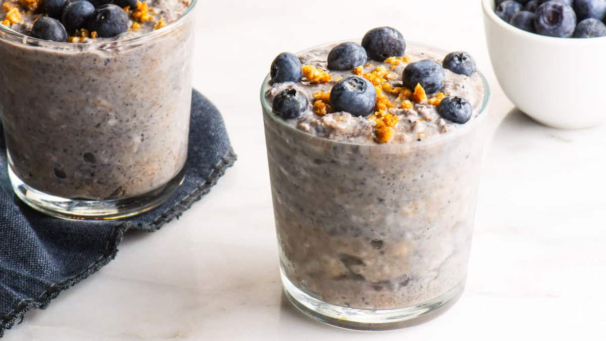 A glass jar filled with blueberry overnight oats, layered with fresh blueberries, chia seeds, and rolled oats.