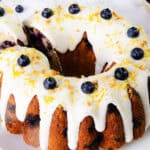 A lemon blueberry cake topped with white icing and blueberries.