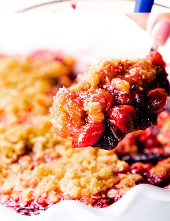 A spoonful of cherry crumble being served.