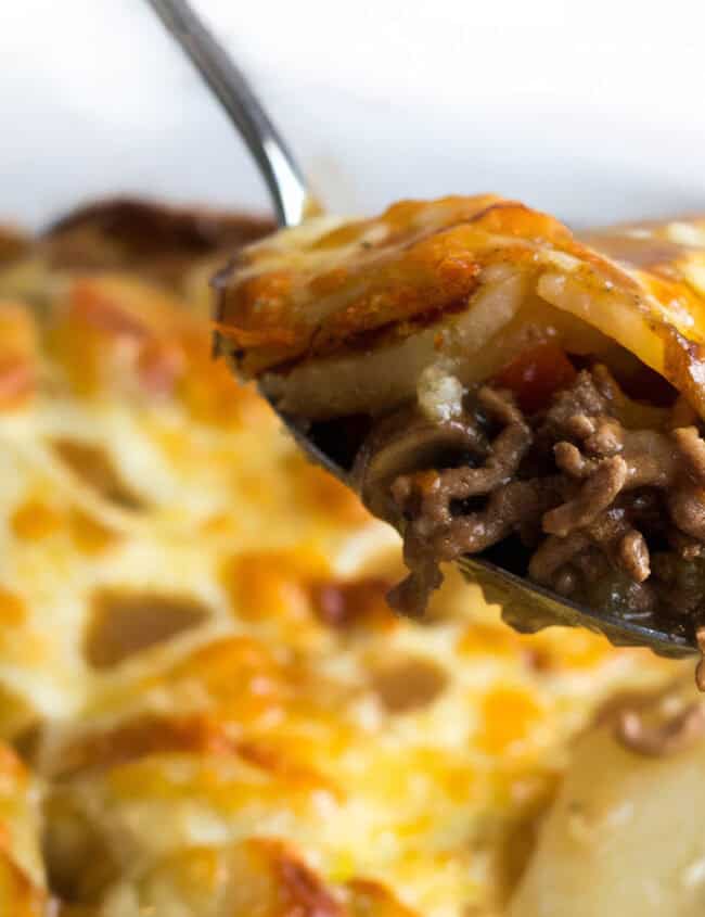 A spoon serving cottage pie stopped with cheesy potatoes.