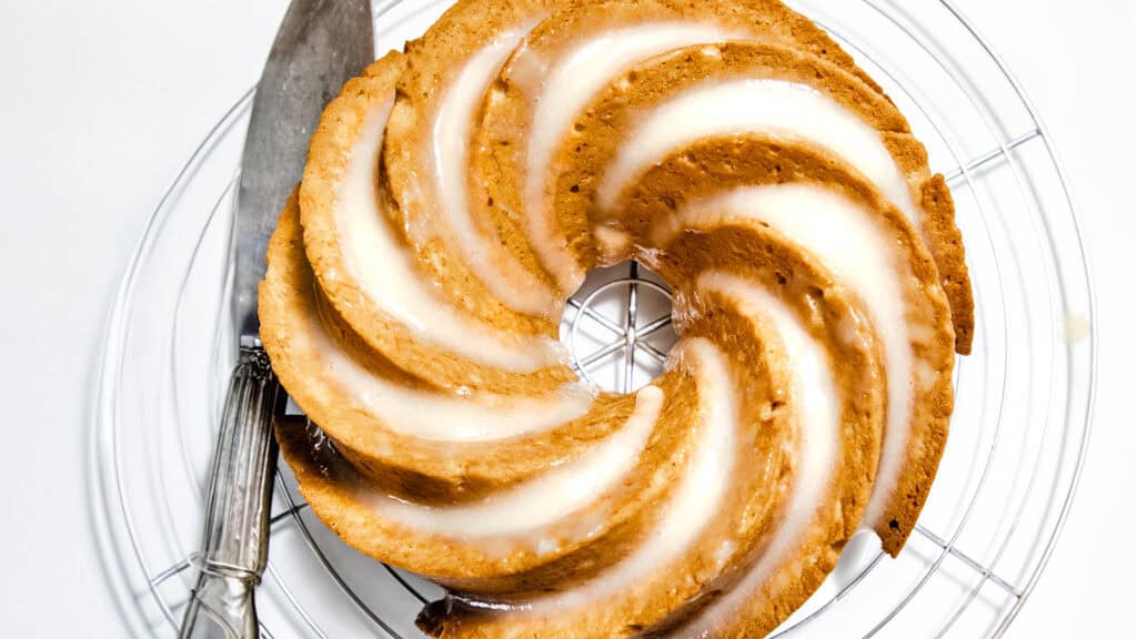 A Bundt cake with Cream Cheese Icing on a cooling rack.