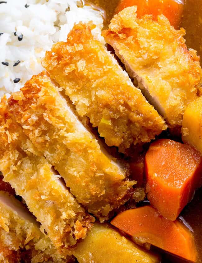 A close up image of Katsu Curry over rice in a white bowl.