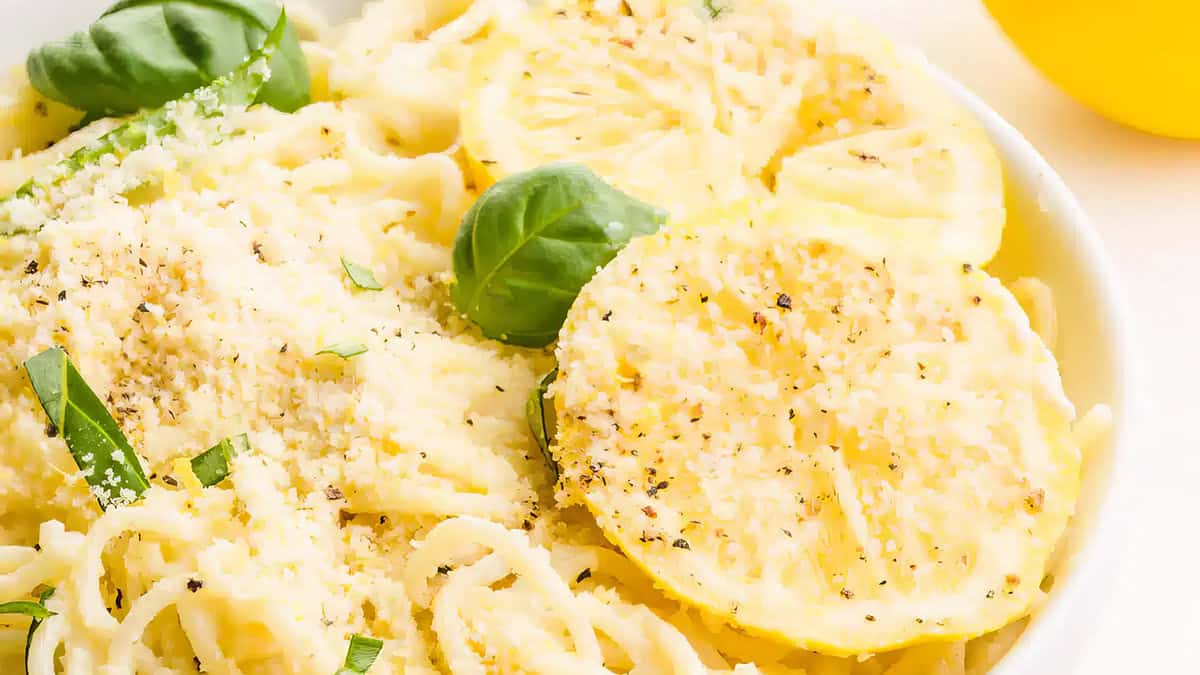 A close up image of lemon spaghetti on a plate garnished with a lemon slice.