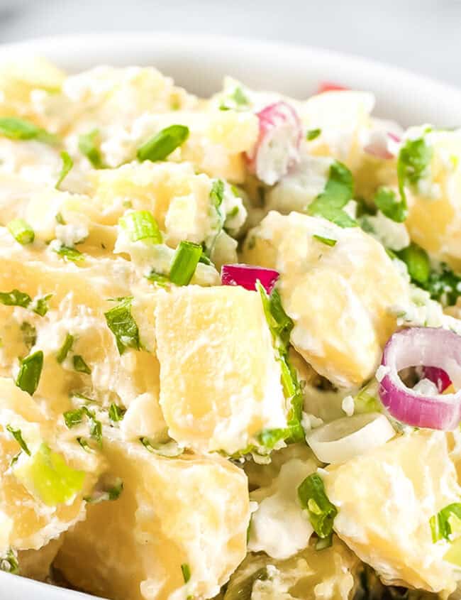 A close up image of potato salad in a white bowl.