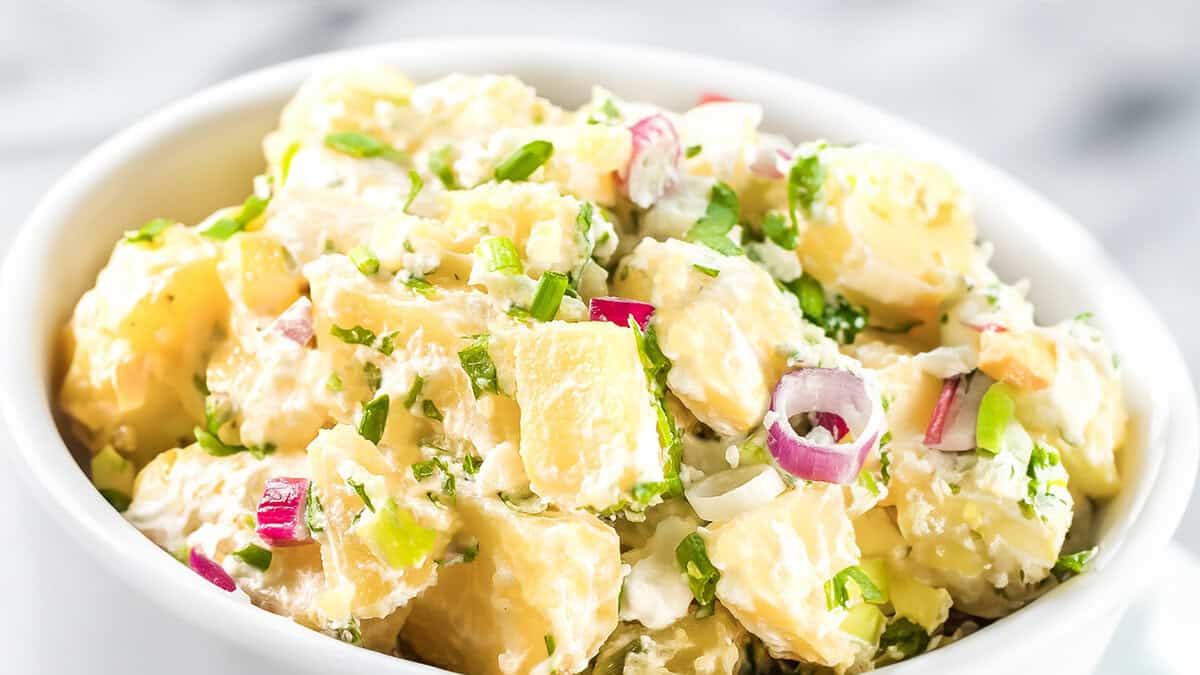 A close up image of potato salad in a white bowl.