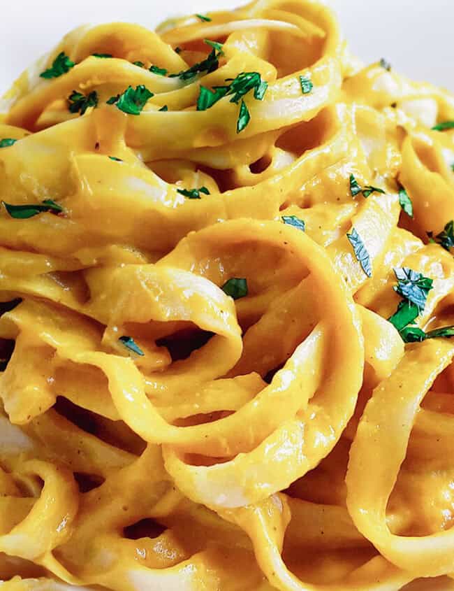 A close up image of fettuccine pasta in a vibrant yellow cream sauce.