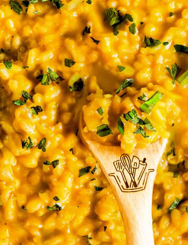 Saffron Risotto in a black pan with a wooden spoon.