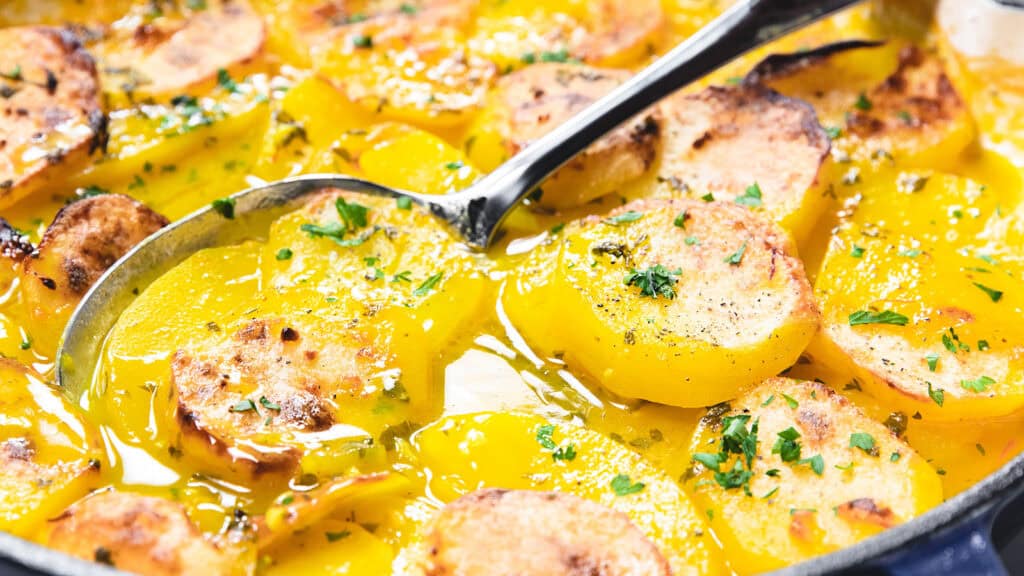 A spoonful of saffron potato casserole being scooped from a pan.