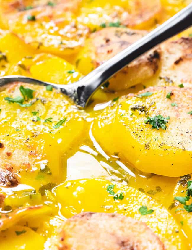 A spoonful of saffron potato casserole being scooped from a pan.