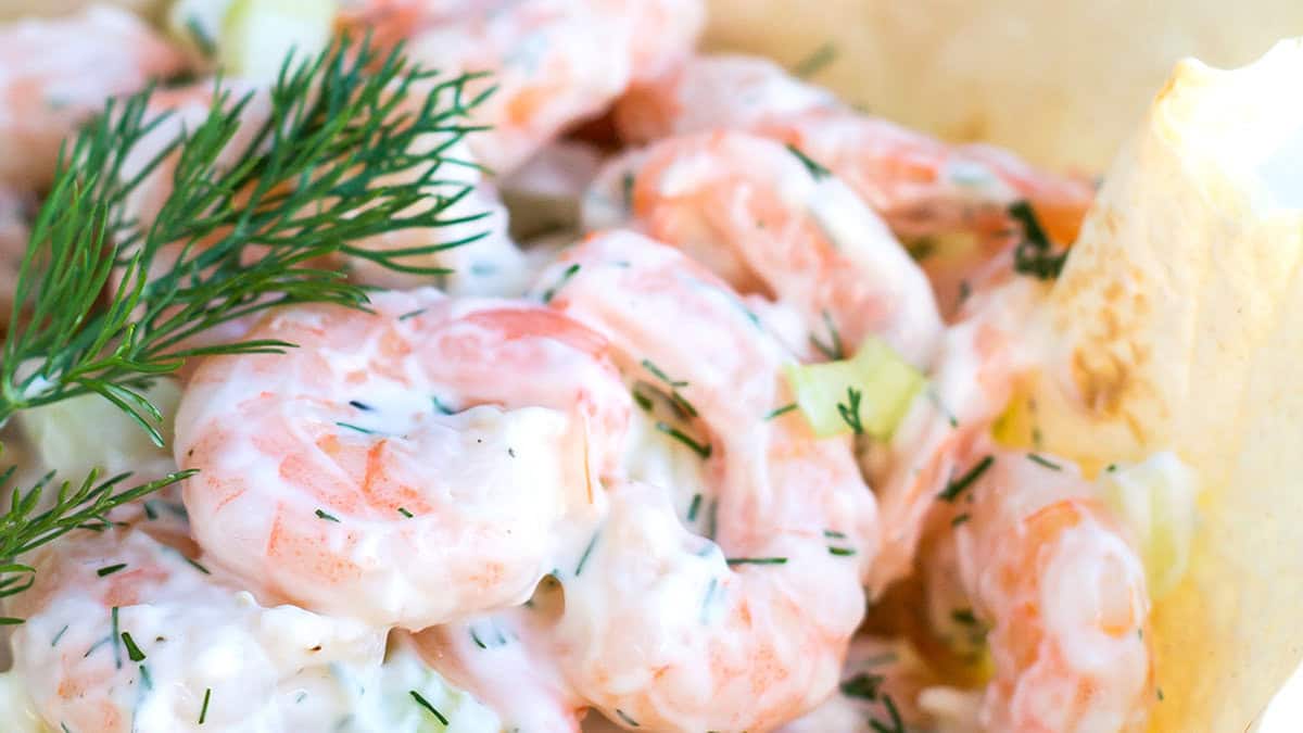 Shrimp salad with a lemon wedge and dill garnish.