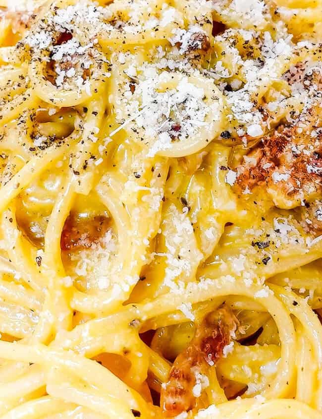 Spaghetti Alla Carbonara piled high on a plate with crisp guanciale.