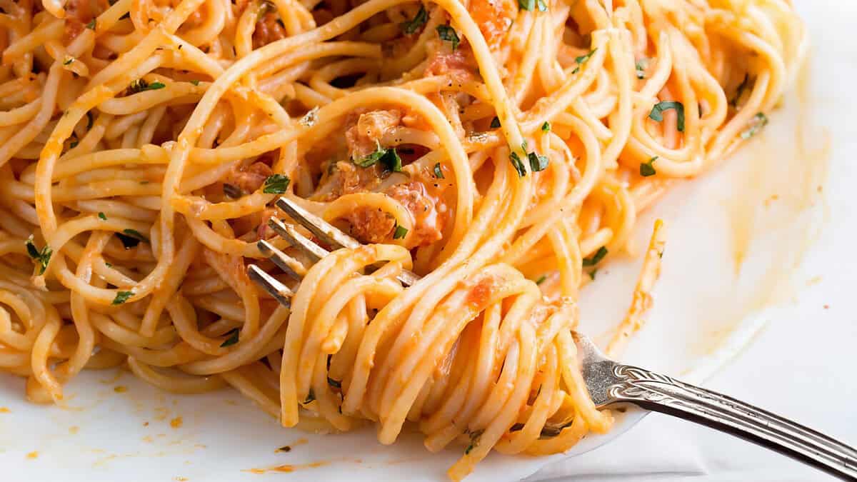 Spaghetti in a tomato cream sauce on a plate with a fork.