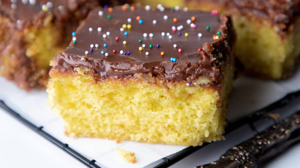 A close up image of a slice of yellow cake with chocolate frosting.