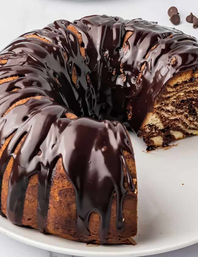 A Bundt cake with zebra stripes in the inside glazed with chocolate glaze.