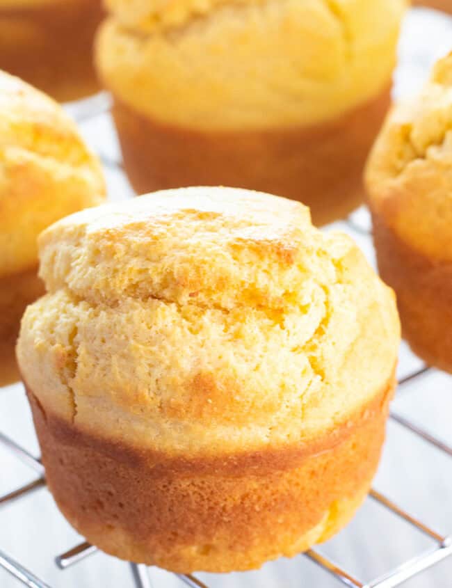 Freshly baked corn muffins cooling on a cooling rack.