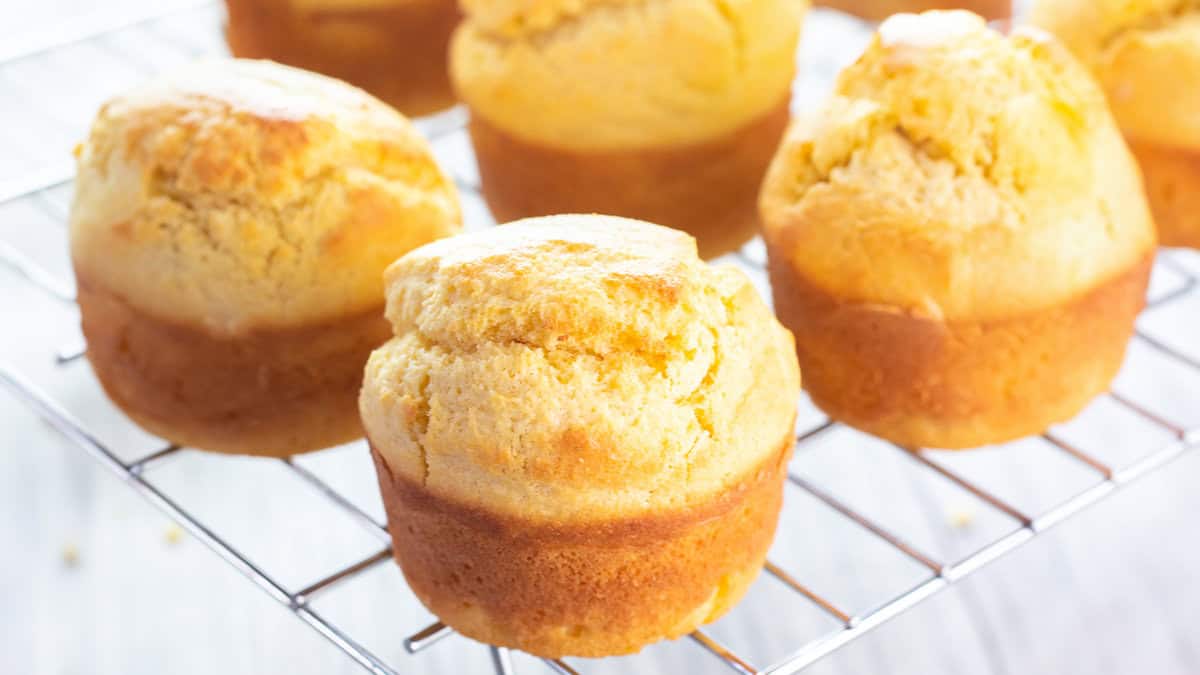 Freshly baked corn muffins cooling on a cooling rack.