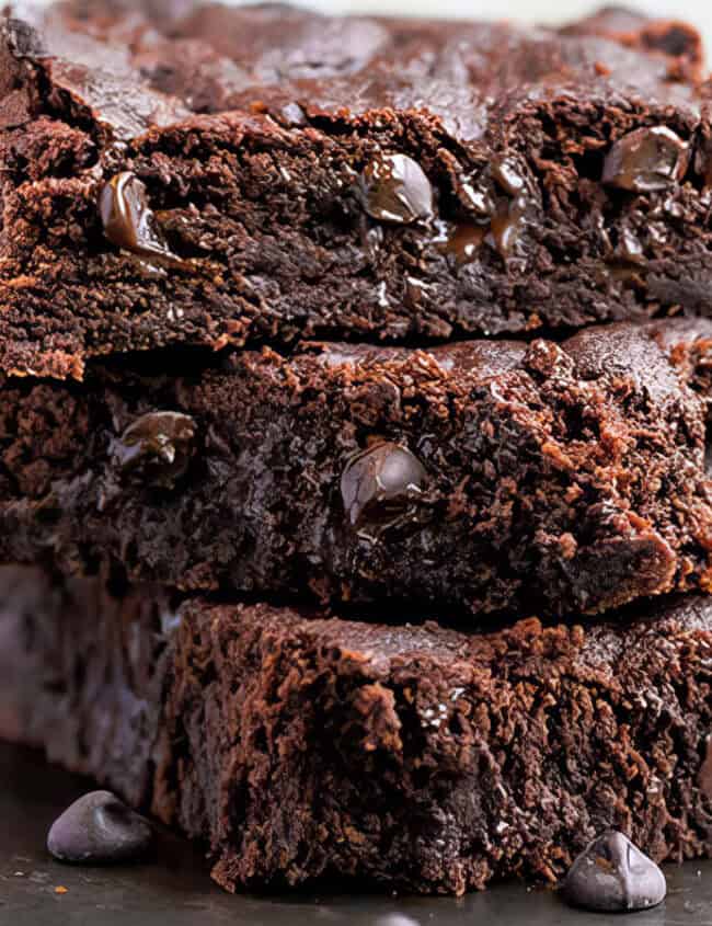 A stack of three double chocolate chip bars with melted chocolate chip cookies dotted throughout.