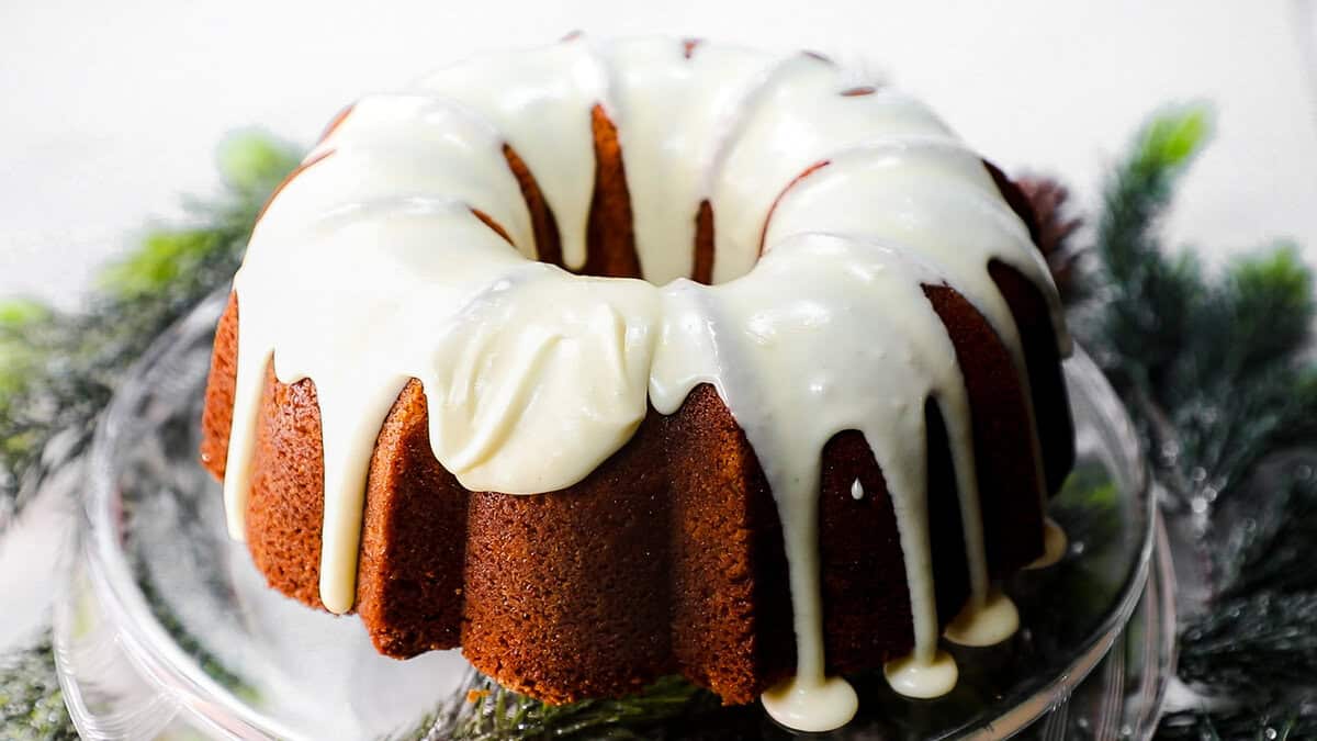 Eggnog Cake on a glass cake stand topped with icing.