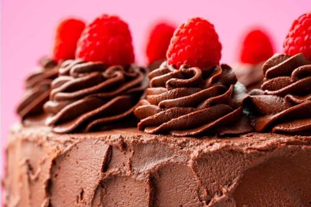 Chocolate Raspberry Cake topped with swirls of chocolate frosting and raspberries.