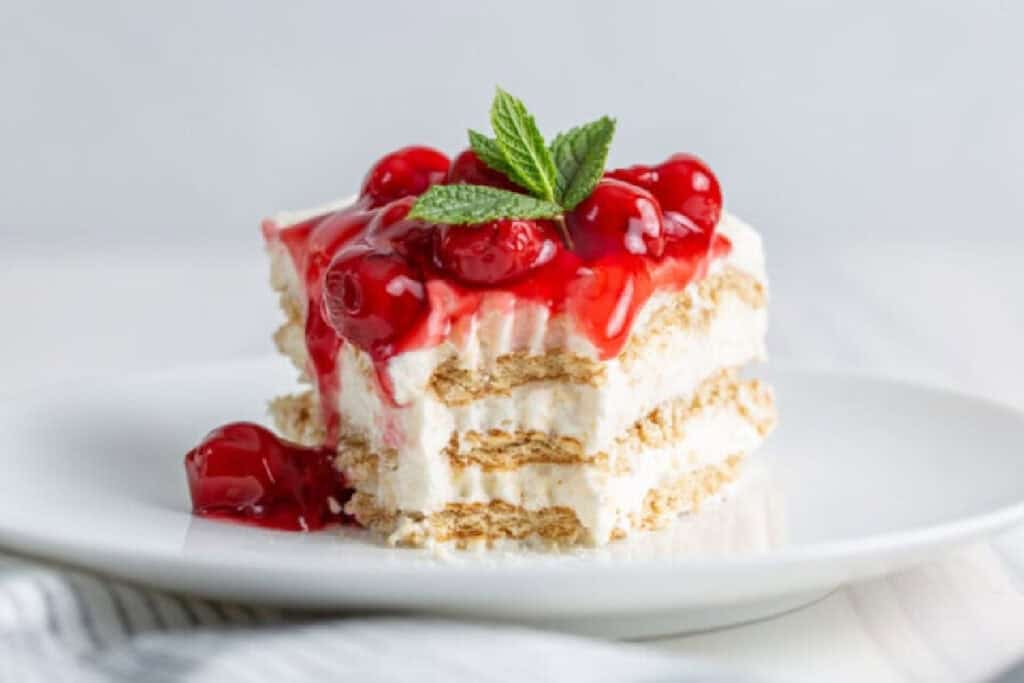 A slice of No Bake Cherry Cheesecake Icebox Cake with a forkful cut from it.
