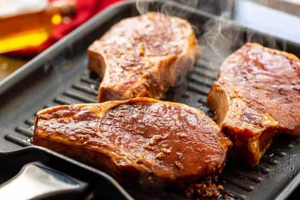 Porkchops cooking on a grill.