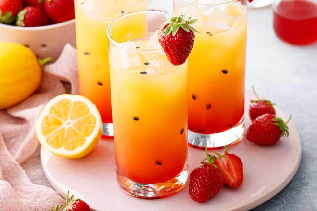 A colorful Strawberry Passionfruit Lemonade garnished with strawberries.