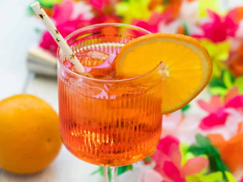 A close up image of a Aperol Spritz with a slice of orange on the glass.