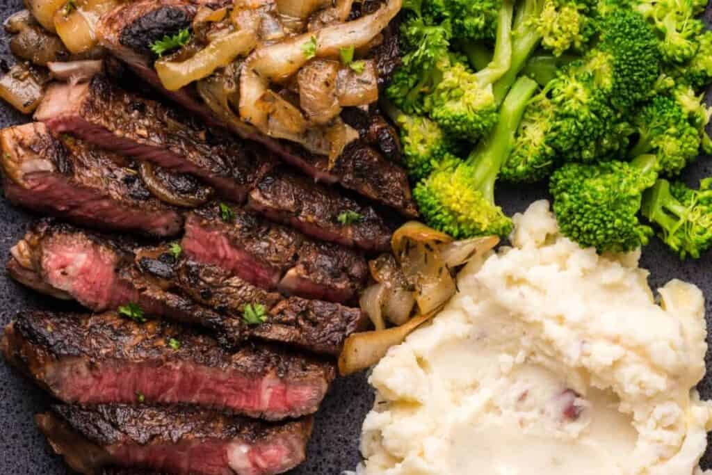 A sliced Baked Garlic Balsamic Steak with broccoli and potatoes.