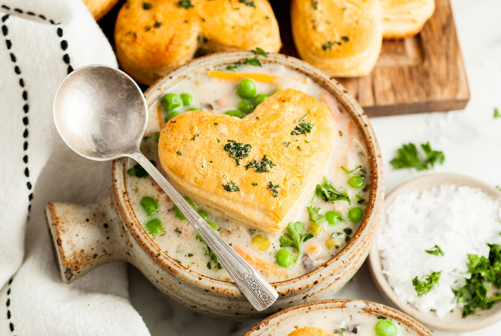 A bowl of chicken soup with puff pastry in the shape of a heart.