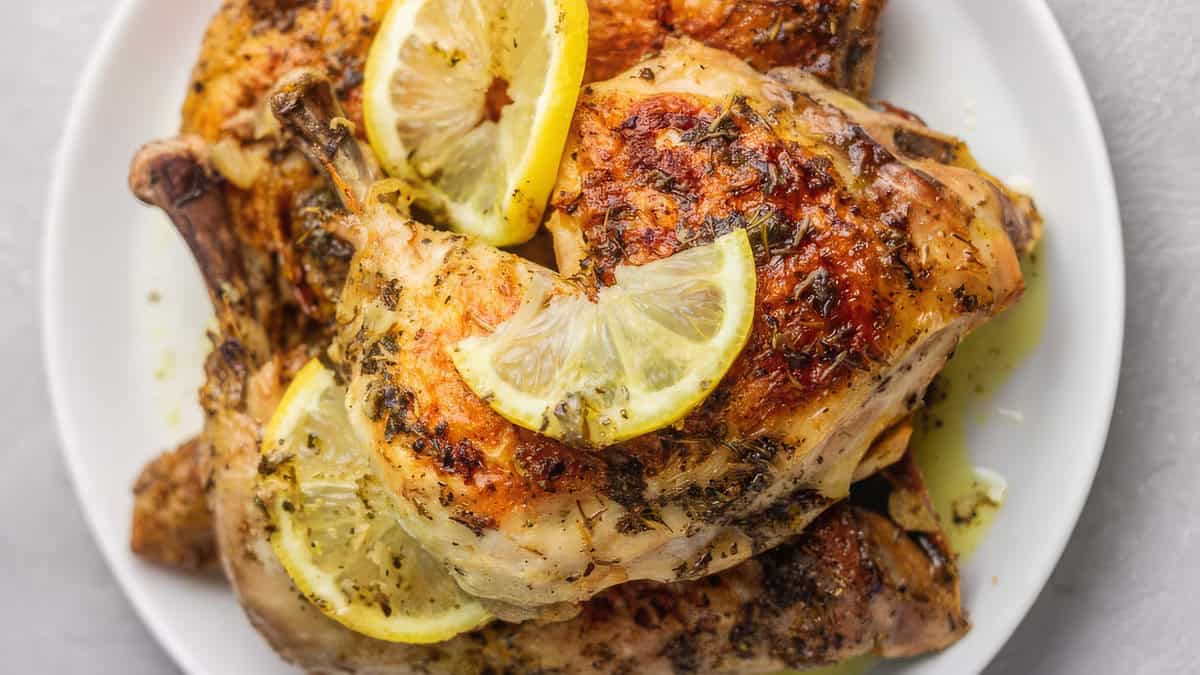 A close up image of a platter of chicken legs garnished with lemon slices.