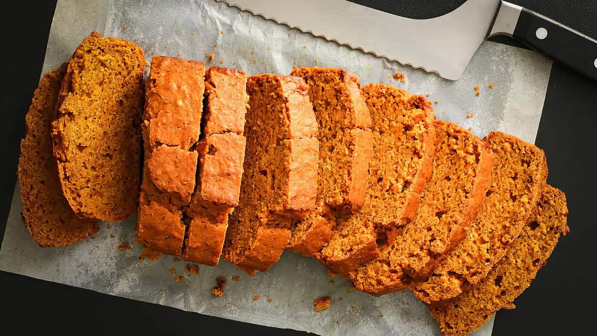 A sliced vegan pumpkin bread loaf on a board.