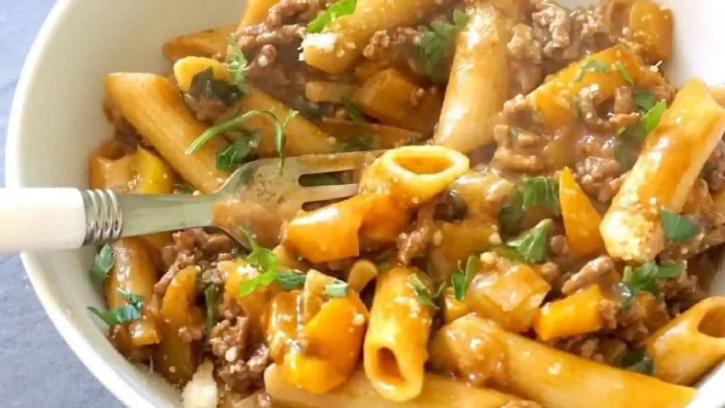 Pasta with ground beef in a white bowl.