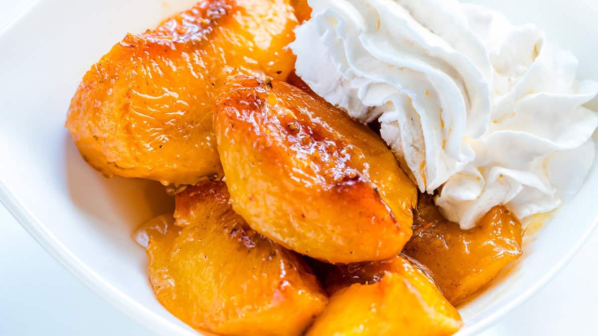 a white bowl of warn peaches and cream.