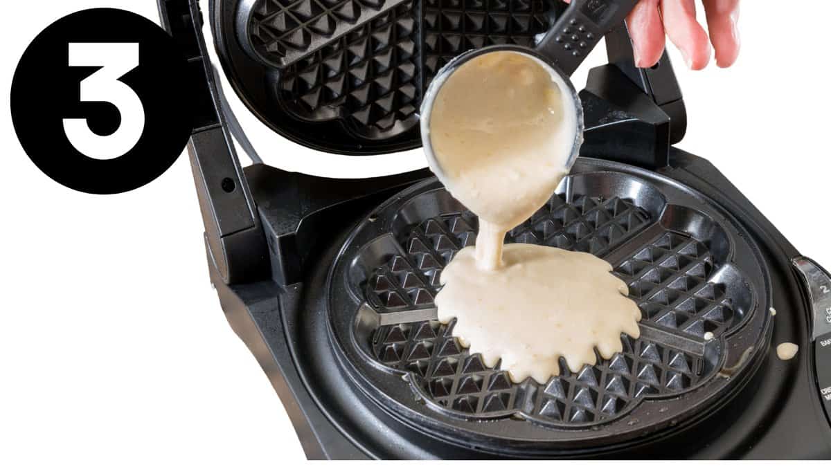 a waffle maker with batter being poured into it.