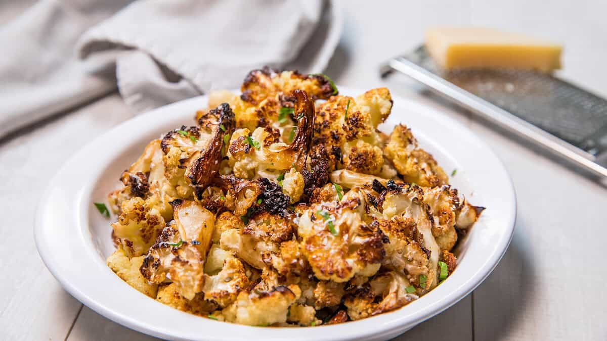 roasted cauliflower in a bowl ready to serve with a fork beside it.