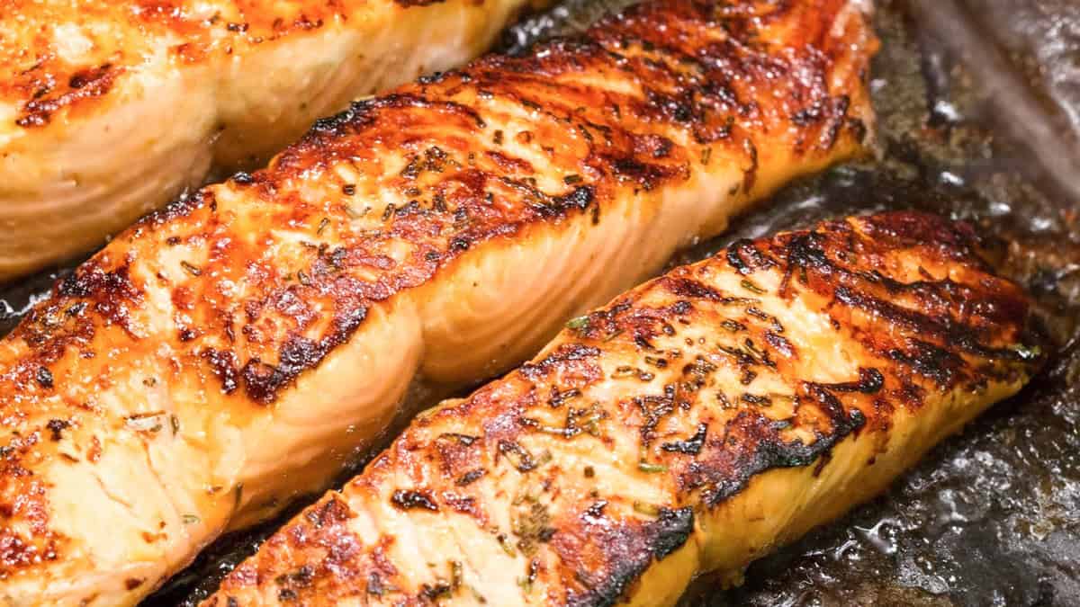 A close up image of Seared Salmon cooking in a black pan.